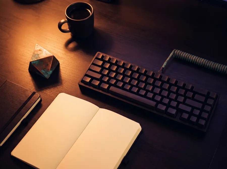 A workspace at night: keyboard, open notebook and a warm desk lamp