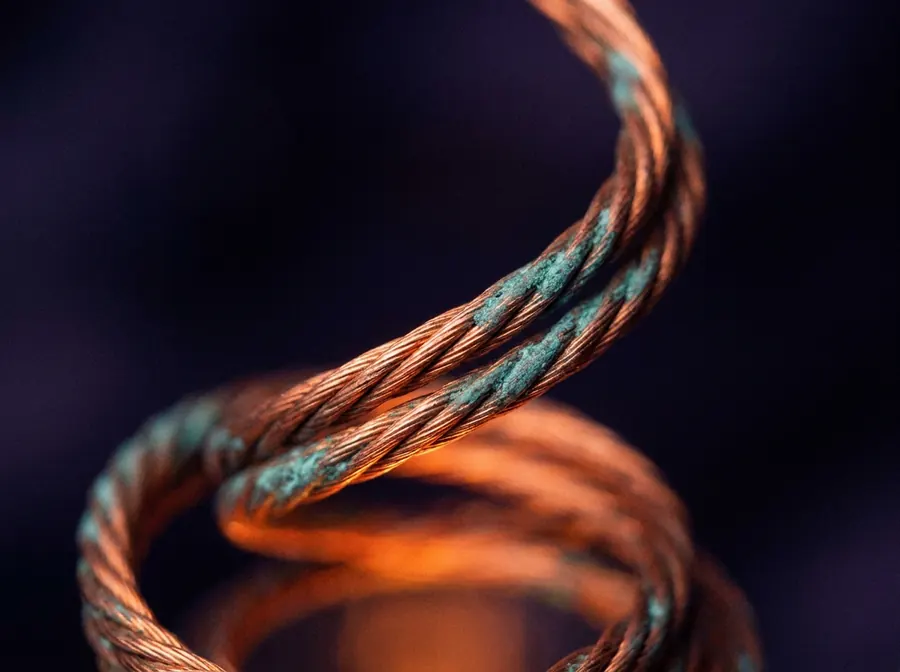 Copper wire coiling upward, catching warm light